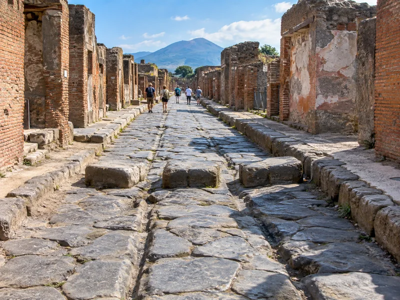 Antike gepflasterte Straße in Pompeji mit Trittsteinen und Ruinen von Häusern